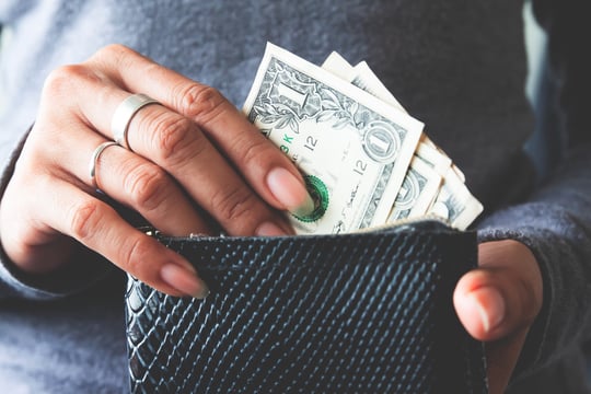 Close-up of hands pulling one-dollar bills out of a black wallet
