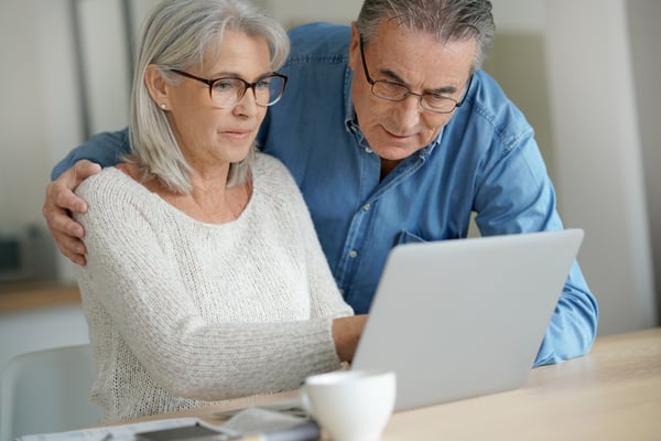 Older couple looks at a laptop together at a table at home