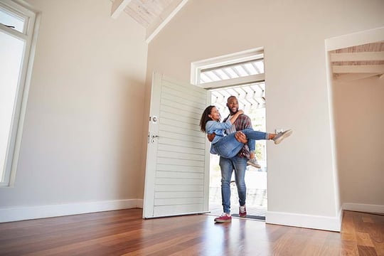 Newlywed couple walking into their new home