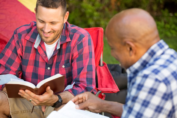 Two men sitting outside discussing the Bible