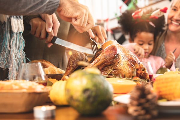 A family cutting into their Thanksgiving turkey.