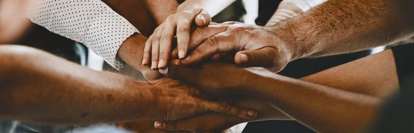 Close-up of a group of people stacking their hands together