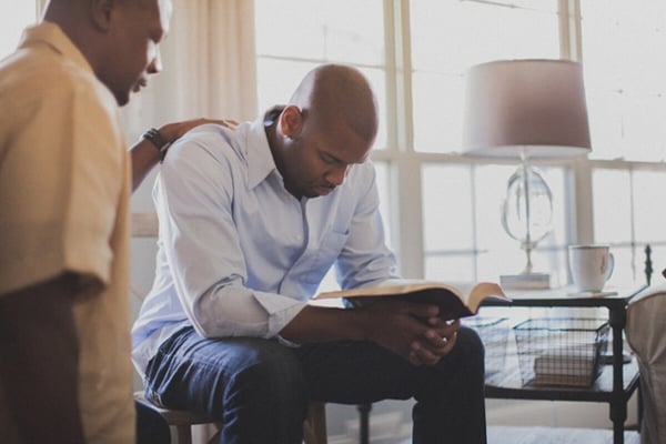 Man praying with another man