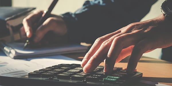 mans hands using calculator and budget sheet