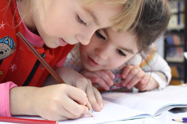 two girls writing in a workbook