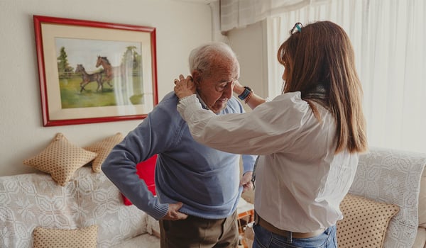 An older dad's sweater collar being adjusted by adult daughter.