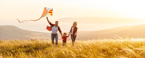 Family running in field with kite