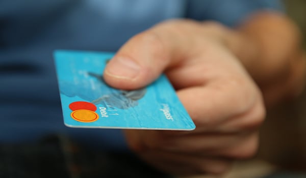 Close-up of a hand holding out a blue debit card