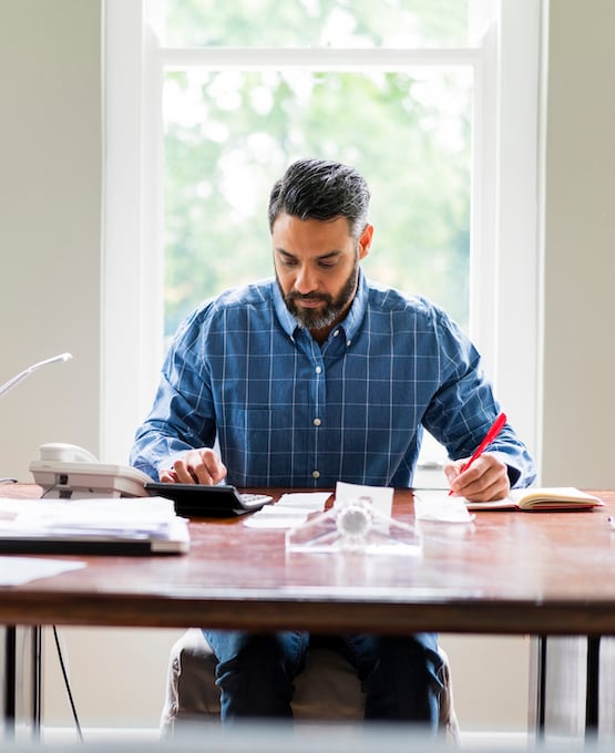Man sitting at table crunching numbers