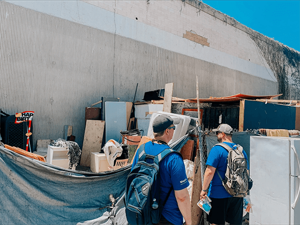 two men looking at pile of old appliances and trash