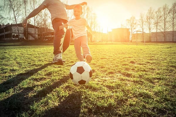 Father and son playing soccer in the park