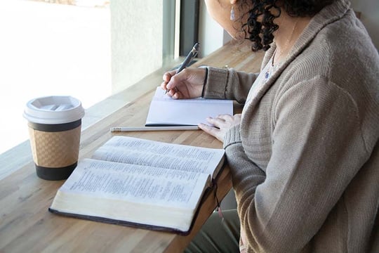 Woman studying her Bible and journaling