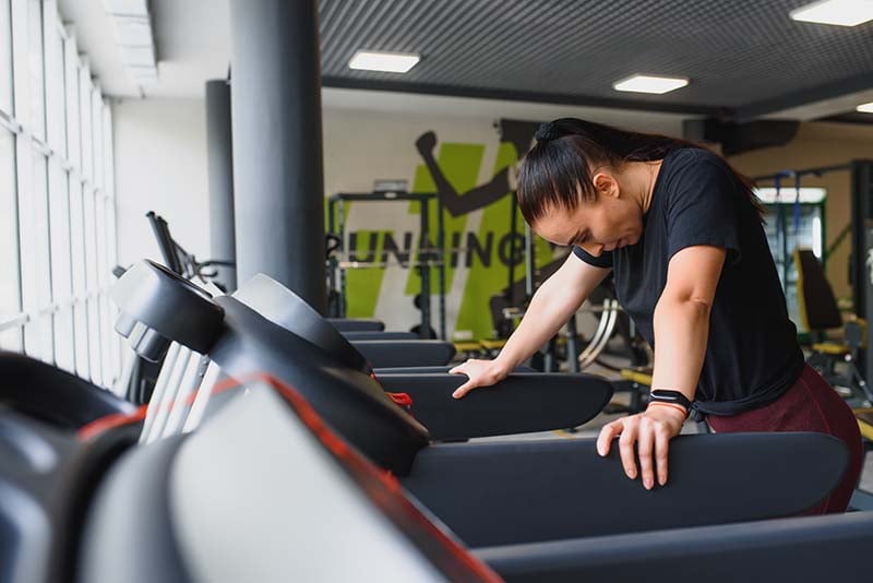 Woman hunched over a treadmill