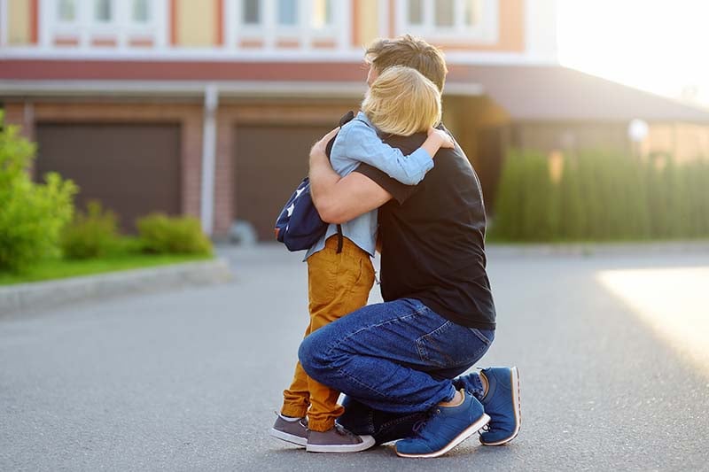 Dad consoling child in front of school