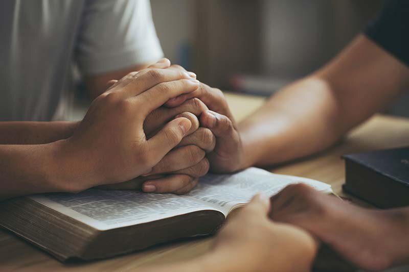 Women holding hands and praying