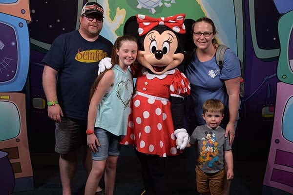 Erika Williams with her husband and two children posing with Minnie Mouse