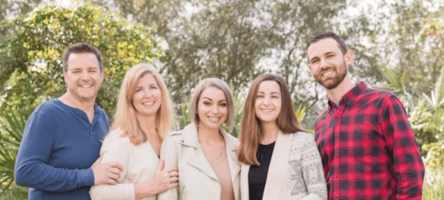 Five smiling adults posing together outdoors, with Fawn Tornicelli second from left