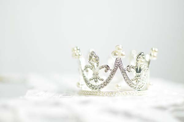 Small silver tiara set with rhinestones and pearls on a soft white surface