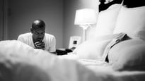 Man kneeling to pray by his bed