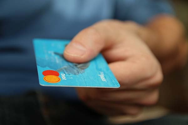 Close-up of a hand holding out a blue debit card
