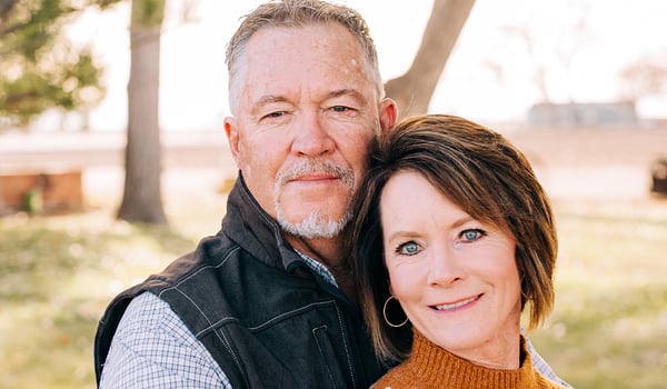 Smiling couple poses cheek to cheek outdoors on a sunny day