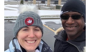 Smiling woman in a knit winter hat and a man in sunglasses take a selfie on a snowy day