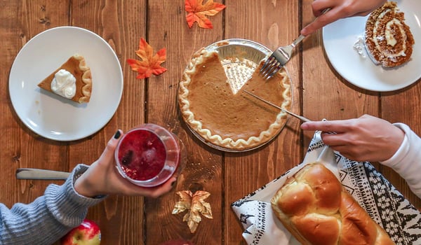 Overhead view of pumpkin pie, braided bread and autumn leaves on a wooden Thanksgiving table
