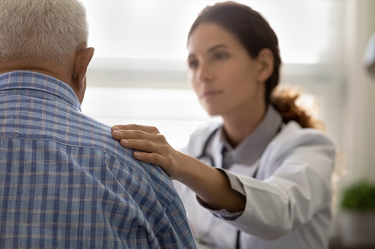 Empathetic doctor giving emotional support to elderly male patient