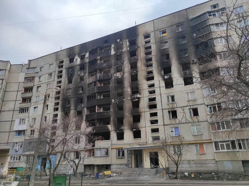 War-damaged apartment block in Ukraine with burned-out windows and black scorch marks up its facade