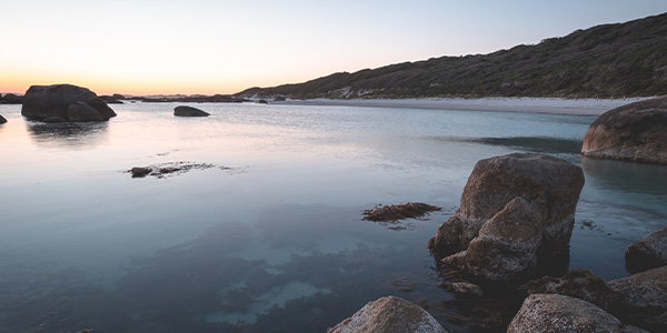 calm lake at sunset with rocks in foreground