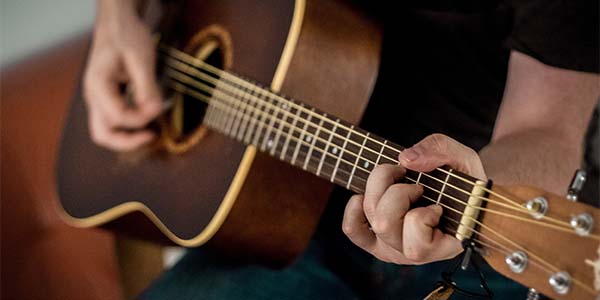 close up of hands playing guitar