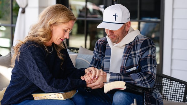 Michael and Karen holding hands in prayer with Bibles in their laps