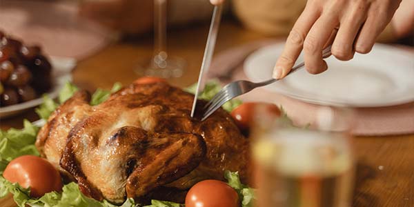 hand cutting into a roasted turkey