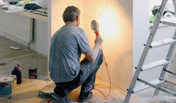 man in unfinished home shining light on wall