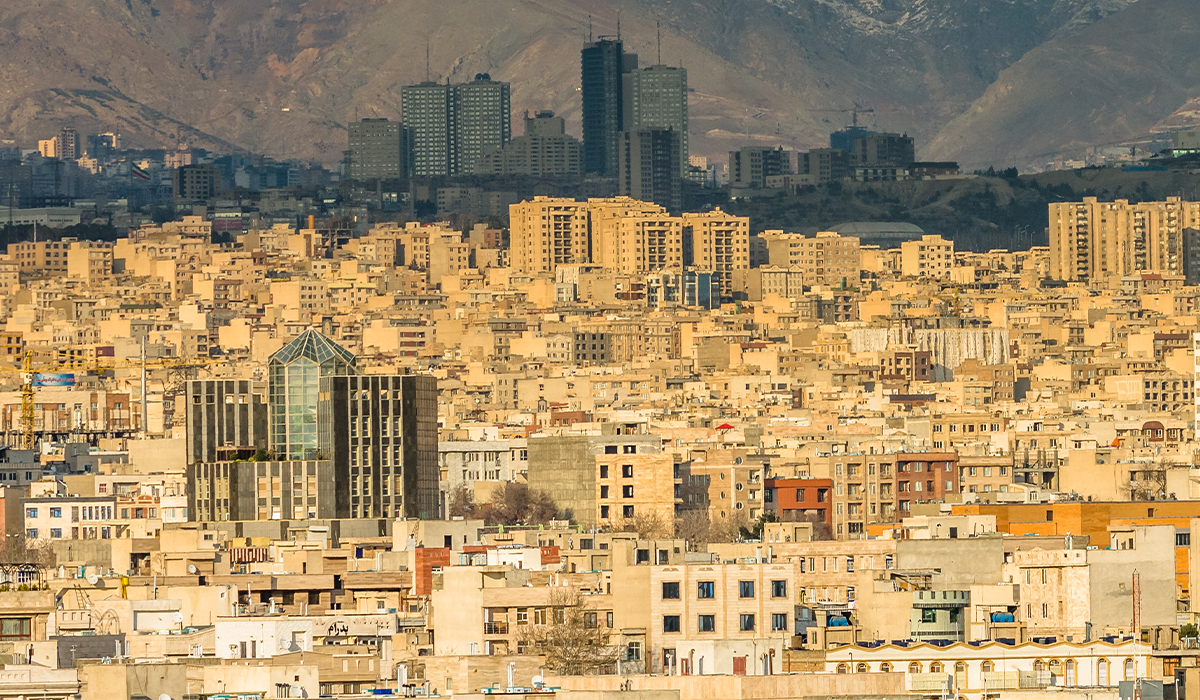 View of Iran with tightly packed buildings and high-rise structures set against a mountainous backdrop.