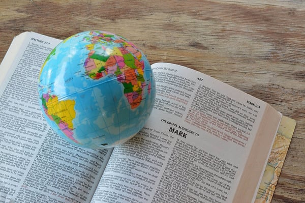 Small globe resting on an open Bible turned to the Gospel of Mark