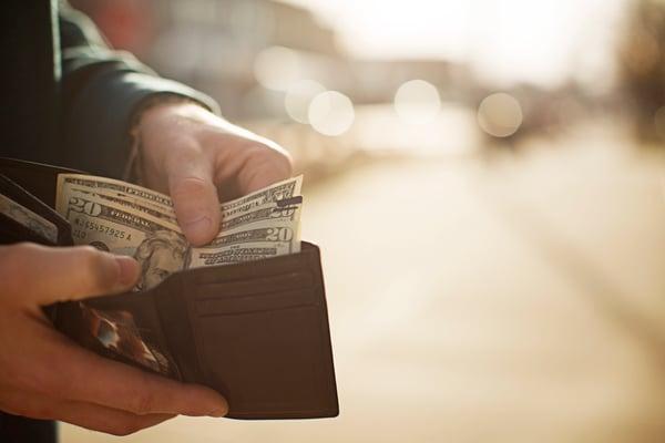 Hands pulling twenty-dollar bills out of a leather wallet