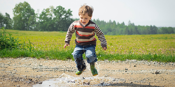 little boy jumping in a puddle
