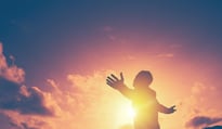 Man with arms outstretched looking at sunrise
