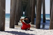 Man laying on the beach under a pier