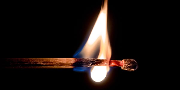 Close-up of a burning matchstick against a black background