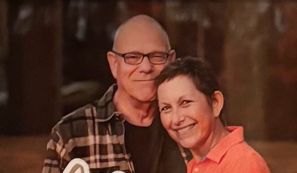 Peggy smiling with her head resting against the shoulder of a man in glasses
