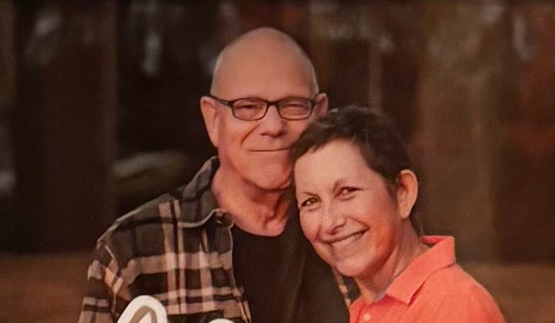 Peggy smiling with her head resting against the shoulder of a man in glasses
