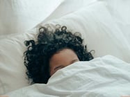 Unrecognizable person sleeping under sheets