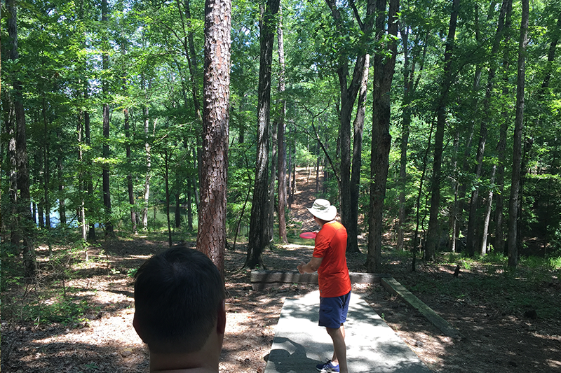 Man playing disc golf on a wooded course