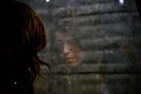 Woman looking out window with a sad expression