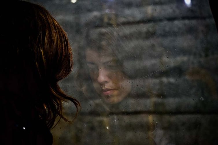Woman looking out window with a sad expression