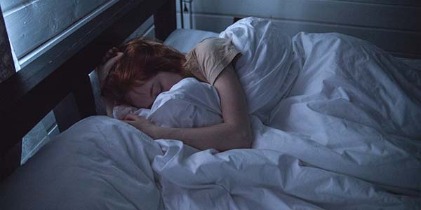 woman asleep in bed hiding her face