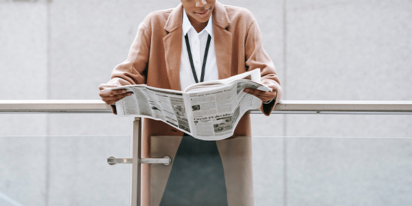 woman leaning on rail reading newspaper