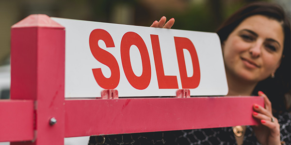 woman next to sold sign